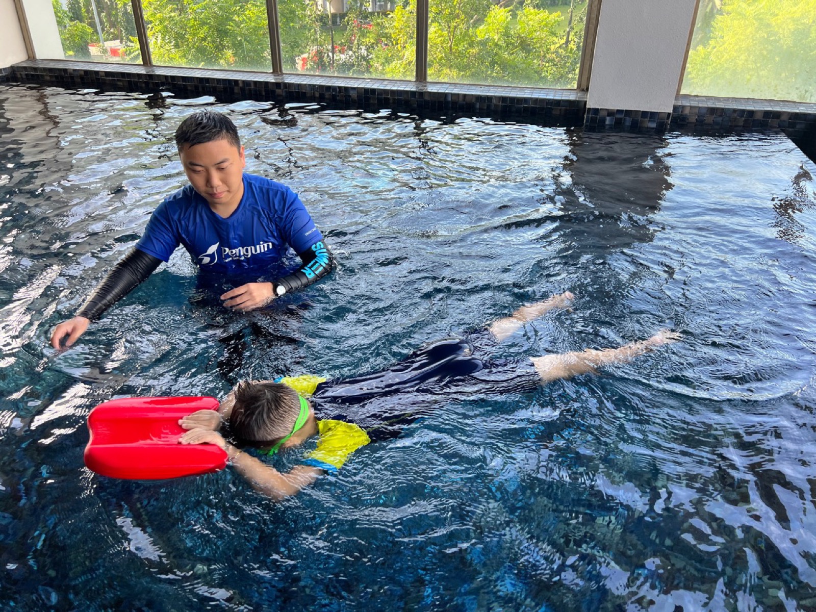 Indoor condominium kickboard swimming lesson with a Penguin coach
